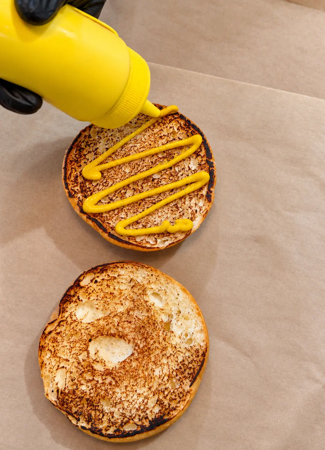 Toasted burger bun being sauced during preparation at ONE Burger